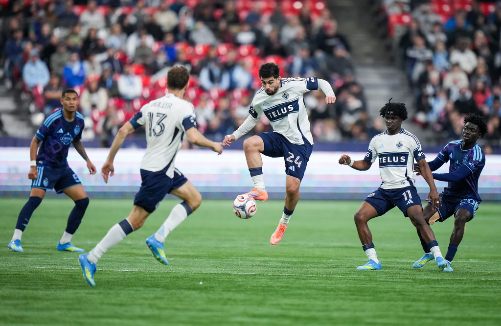 Vancouver Whitecaps' Brian White (24) controls the ball as Emmanuel Sabbi (11), Thomas Muller (13) and Sporting Kansas City's Kwaku Agyabeng (20) and Diego Borges (57) watch during the first half of an MLS soccer match, in Vancouver, on Friday, April 17, 2026. (Darryl Dyck/The Canadian Press via AP)