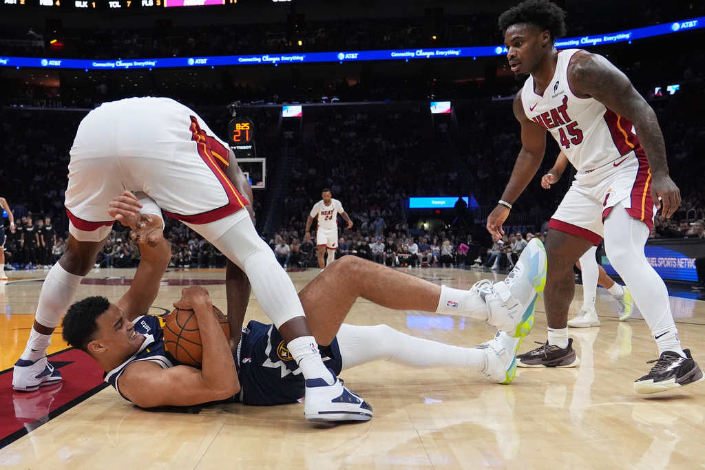 Denver Nuggets forward Spencer Jones (21) falls to the court as he goes for the ball against Miami Heat center Bam Adebayo, left, during the first half of an NBA basketball game, Monday, Dec. 29, 2025, in Miami. (AP Photo/Lynne Sladky)