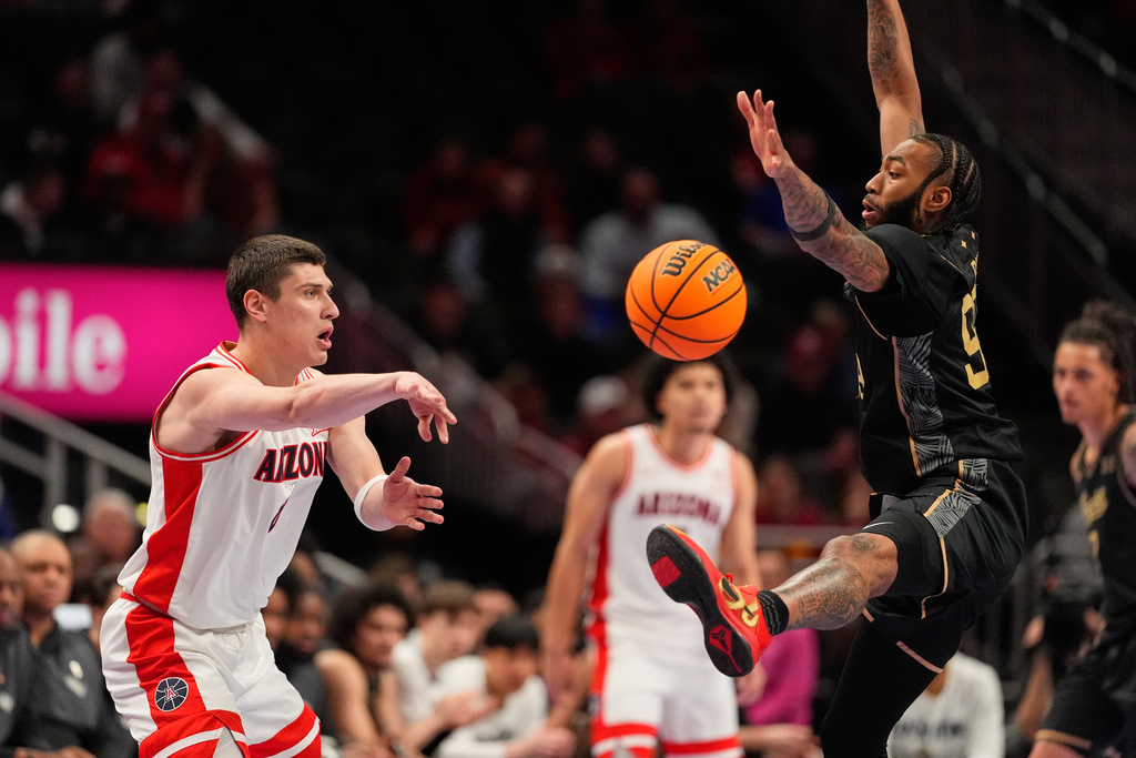 Arizona's Ivan Kharchenkov, left, passes around UCF's Jordan Burks, right, during the first half of an NCAA college basketball game in the quarterfinal round of the Big 12 Conference tournament Thursday, March 12, 2026, in Kansas City, Mo. (AP Photo/Charlie Riedel)