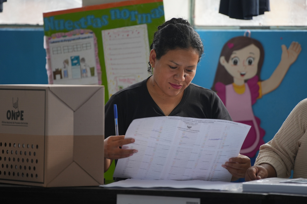 An election official checks voter lists as voting resumes at polling stations affected by delays and logistical problems during general elections in Lima, Peru, Monday, April 13, 2026. (AP Photo/Guadalupe Pardo)