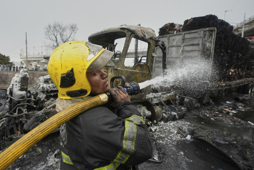 A firefighter sprays a hose after a gas tanker exploded in Mexico City, Wednesday, Sept. 10, 2025. (AP Photo/Fernando Llano)