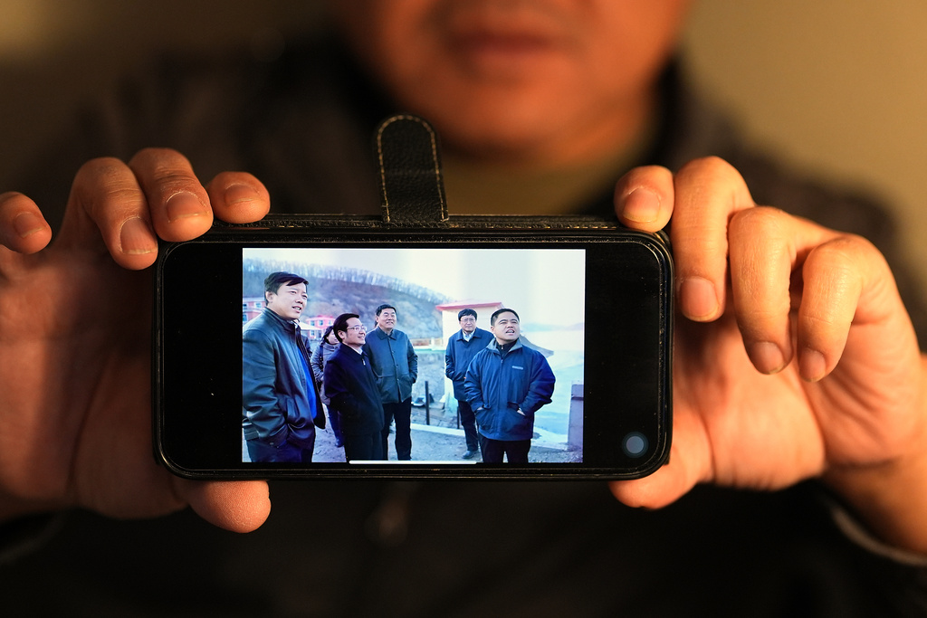 Former Chinese official Li Chuanliang shows one of the few pictures he has of himself, at right, from when he was vice mayor of Jixi, China, in the Mayflower Church community in Midland, Texas, Jan. 20, 2025. (AP Photo/Rebecca Blackwell)