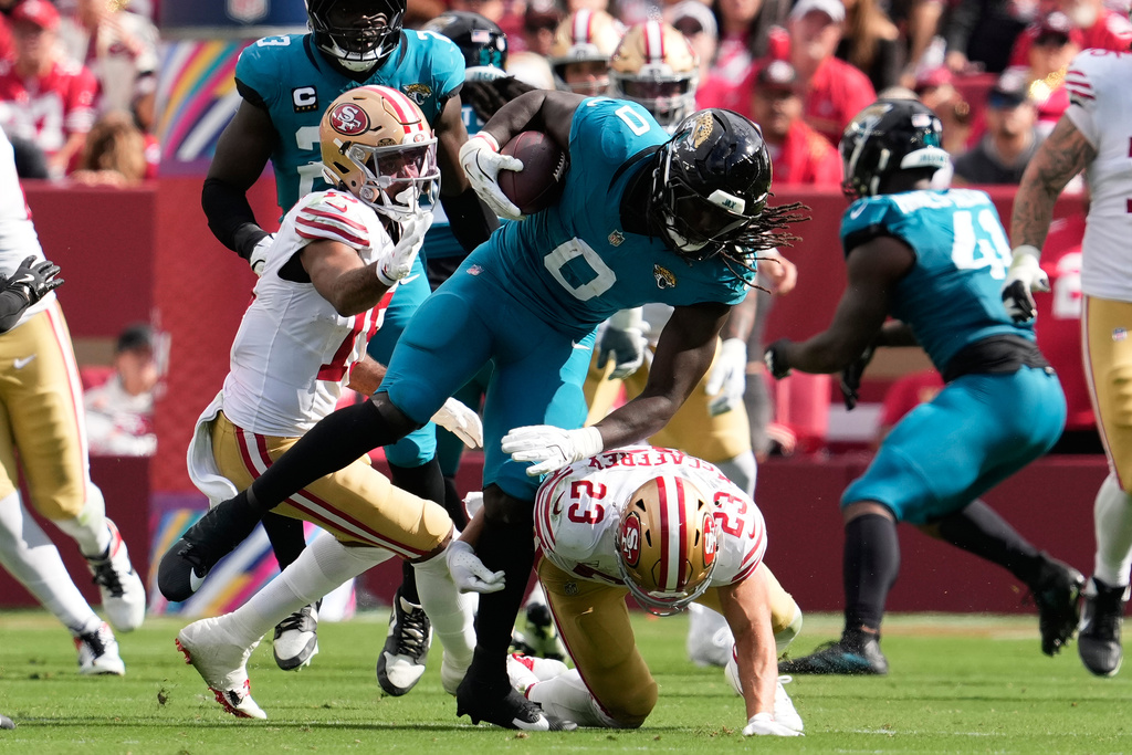 Jacksonville Jaguars linebacker Devin Lloyd (0) returns an interception against San Francisco 49ers running back Christian McCaffrey (23) and wide receiver Jauan Jennings (15) during the second half of a pass an NFL football game in Santa Clara, Calif., Sunday, Sept. 28, 2025. (AP Photo/Godofredo A. Vásquez)