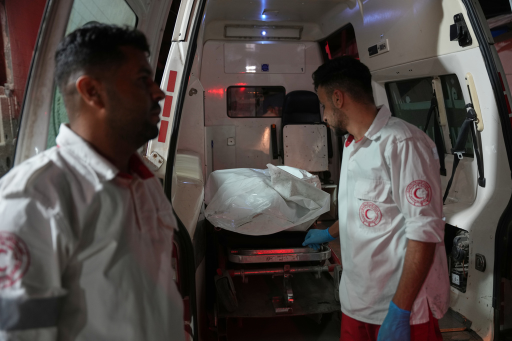Palestinian paramedics stand at the back of an ambulance after arriving at Al-Aqsa Hospital with the body of a person killed in an Israeli military strike on a residential building in Deir al-Balah, central Gaza Strip, Wednesday, July 15, 2026. (AP Photo/Abdel Kareem Hana)