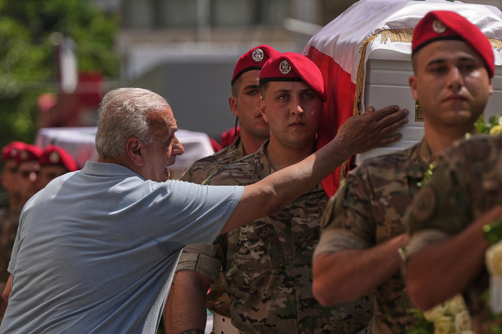 A mourner touches the coffin of the Lebanese army Brig. Gen. Wissam Sabra, who was killed Saturday in south Lebanon along with a captain and a soldier in an Israeli airstrike, during his funeral procession in Beirut, Sunday, June 7, 2026. (AP Photo/Hassan Ammar)