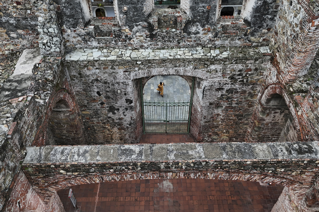 A tourist visits the ruins of Santo Domingo church, built in the 17th century after the city was relocated from its first colonial settlement, which had been destroyed by pirates, in "Casco Viejo," the historic district of Panama City, a UNESCO World Heritage Site, Sunday, Aug. 10, 2025. (AP Photo/Matias Delacroix)