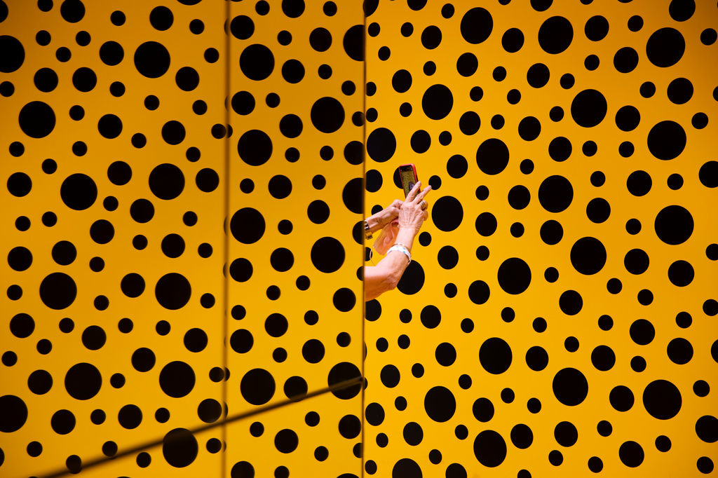 FILE -A woman takes a photo during her visit at the art work 'The Spirits of the Pumpkins Descended into the Heavens' by Yayoi Kusama, part of retrospective exhibition in the Tel Aviv Museum of Art, Israel, Monday, Nov. 15, 2021. (AP Photo/Oded Balilty, File)