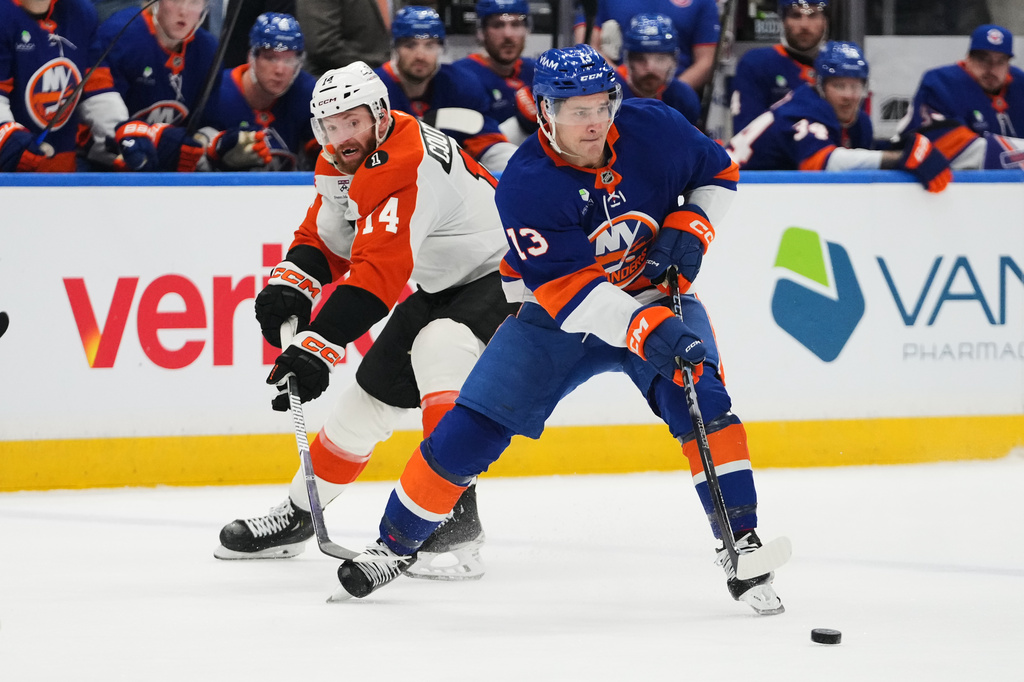 Philadelphia Flyers' Sean Couturier (14) defends New York Islanders' Mathew Barzal (13) during the second period of an NHL hockey game Friday, April 3, 2026, in Elmont, N.Y. (AP Photo/Frank Franklin II)