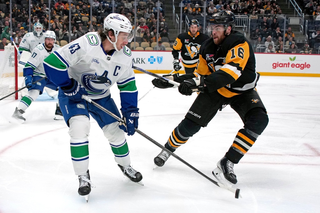 Vancouver Canucks' Quinn Hughes (43) clears the puck in front of Pittsburgh Penguins' Justin Brazeau (16) during the second period of an NHL hockey game in Pittsburgh, Tuesday, Oct. 21, 2025. (AP Photo/Gene J. Puskar)