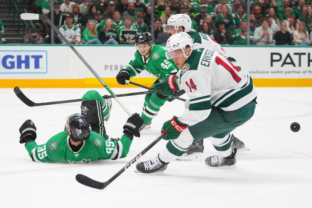 Dallas Stars center Matt Duchene (95) hits the ice while attacking against Minnesota Wild center Joel Eriksson Ek (14) and defenseman Jake Middleton, back right, during the first period of an NHL hockey game Tuesday, Oct. 14, 2025, in Dallas. (AP Photo/Julio Cortez)