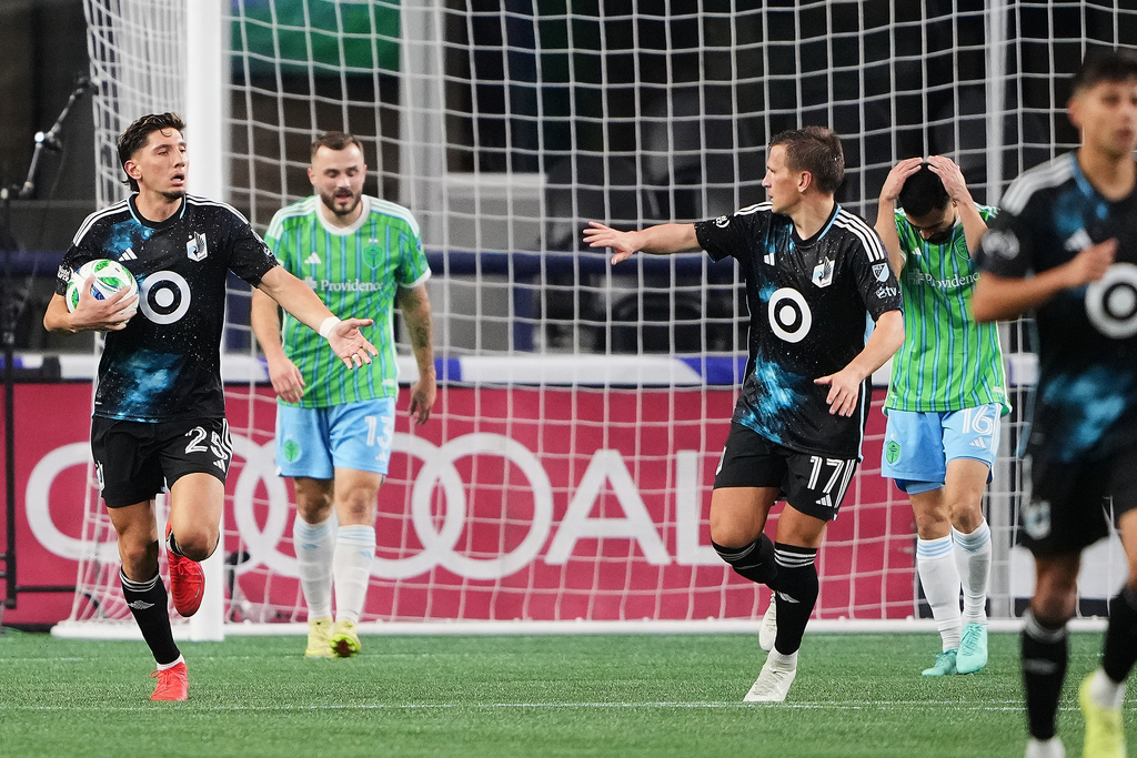 Minnesota United defender Nectarios Triantis (25) celebrates his goal with midfielder Robin Lod (17) as Seattle Sounders forward Jordan Morris (13) and midfielder Alex Roldan (16) react during the first half of Game 2 in the first round of MLS soccer's Western Conference playoffs Monday, Nov. 3, 2025, in Seattle. (AP Photo/Lindsey Wasson)
