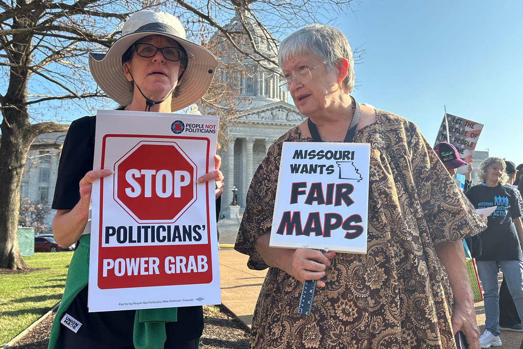 Shellie Rodgers, left, and Melinda Elmore, right, hold signs protesting new U.S. House districts passed by the state Legislature during a rally on March 10, 2026, outside the state Capitol in Jefferson City, Mo. (AP Photo/David A. Lieb)