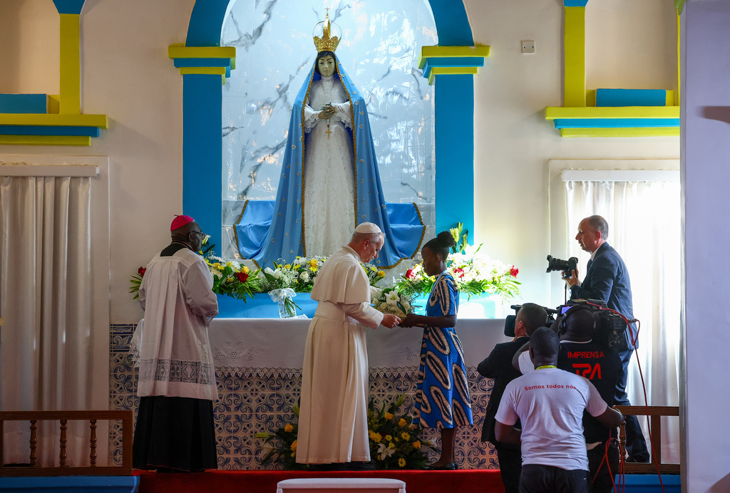 Pope Leo XIV receives flowers he put under the statue of the Virgin Mary in the Church of Our lady of Muxima, on the seventh day of an 11-day apostolic journey to Africa, in Muxima, Angola, Sunday, April 19, 2026. (Guglielmo Mangiapane/Pool Photo via AP)