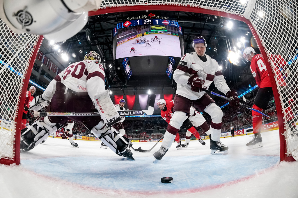 Switzerland's Damien Riat, back center, scores their third goal pasat Latvia's goaltender Kristers Gudlevskis, left, and Alberts Smits during the Group A preliminary round game between Switzerland and Latvia at the men's ice hockey world championship, Saturday, May 16, 2026, in Zurich, Switzerland. (Claudio Thoma/Keystone via AP)
