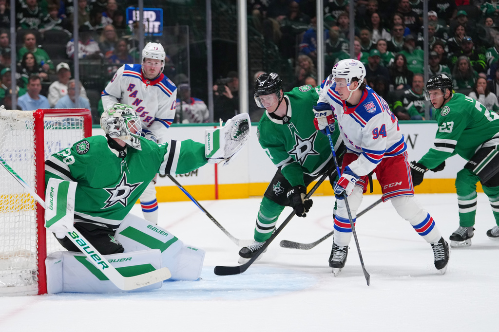 Dallas Stars goaltender Jake Oettinger, left, gloves a shot by the New York Rangers during the second period of an NHL hockey game Saturday, April 11, 2026, in Dallas. (AP Photo/Julio Cortez)