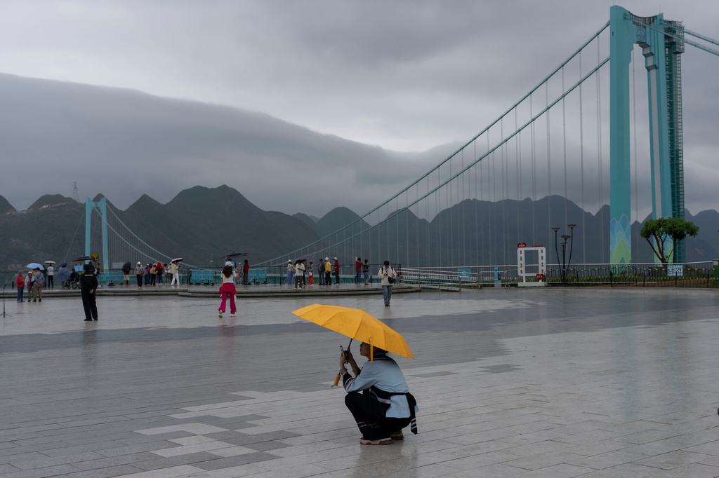 A worker rests under an umbrella near the Huajiang Grand Canyon Bridge, considered to be the world’s highest bridge, in Anshun in southwestern China's Guizhou province on Friday, May 29, 2026. (AP Photo/Ng Han Guan)