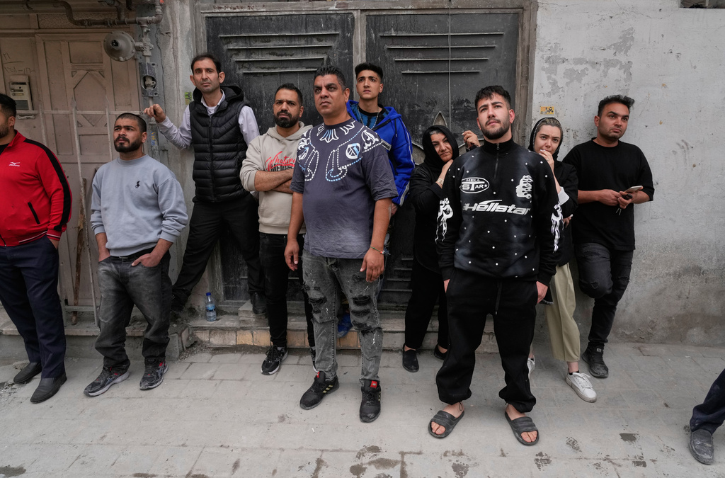 Residents look on as first responders inspect the rubble and search for victims at a residential building hit in an earlier U.S.-Israeli strike in Tehran, Friday, March 27, 2026. (AP Photo/Vahid Salemi)