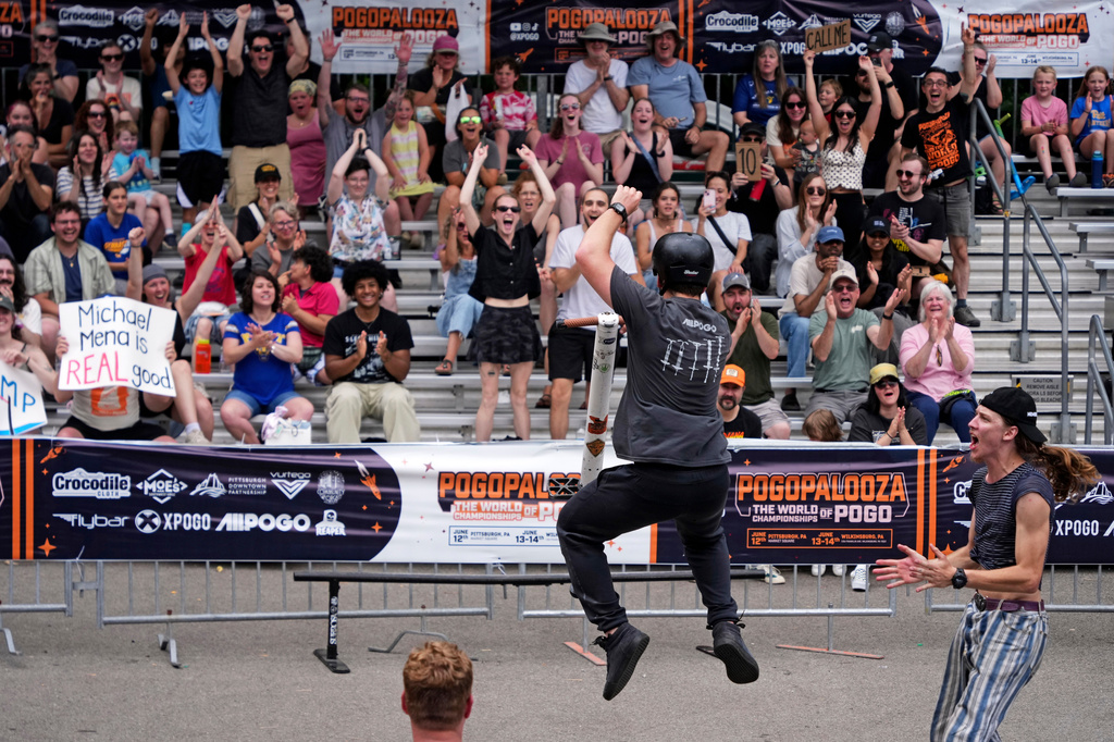 Pogo athlete Michael Mena, center, celebrates after sticking his landing after completing an award winning trick during the Best Trick competition of Pogopalooza 2026 in Wilkinsburg, Pa., Sunday, June 14, 2026. (AP Photo/Gene J. Puskar)