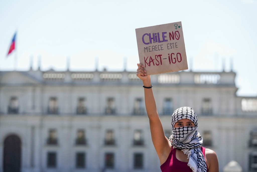 A woman holds a banner that reads in Spanish, "Chile does not deserve this punishment," a pun in reference to Chile's President-elect Jose Antonio Kast, during an International Women's Day protest in Santiago, Chile, Sunday, March 8, 2026. (AP Photo/Esteban Felix)