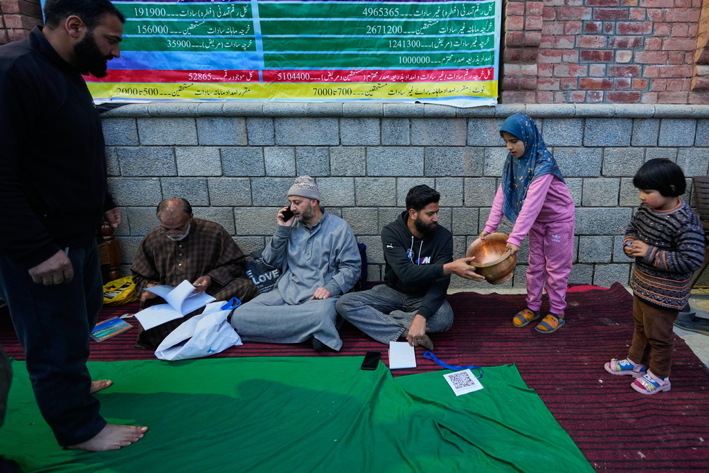A girl donates a copper vessel during a relief drive for Iran in Budgam, Indian-controlled Kashmir, Monday, March 23, 2026. (AP Photo/Mukhtar Khan)