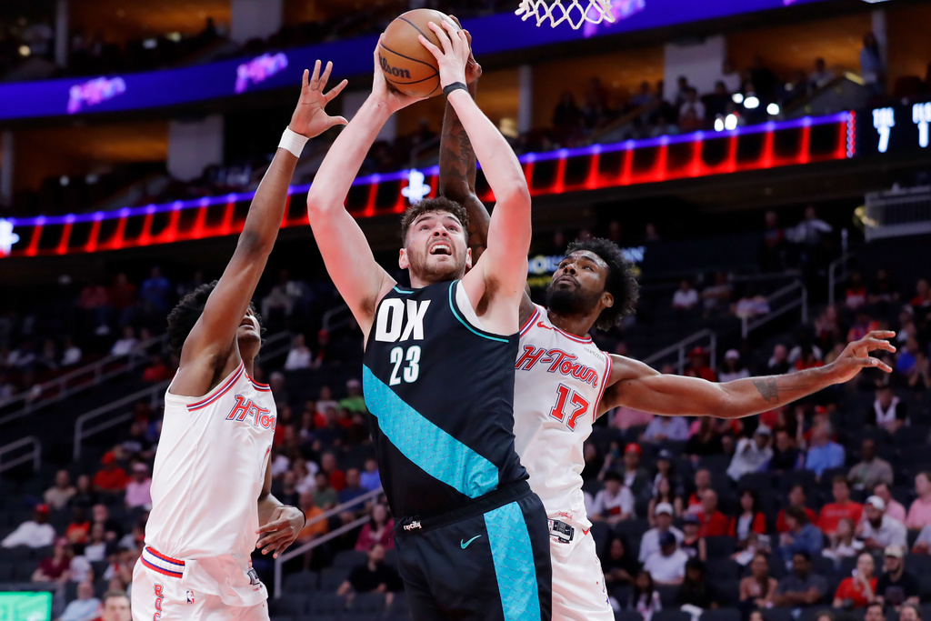 Portland Trail Blazers center Donovan Clingan (23) puts up a shot between Houston Rockets guard Amen Thompson, left, and forward Tari Eason (17) during the first half of an NBA basketball game Friday March 6, 2026, in Houston. (AP Photo/Michael Wyke)