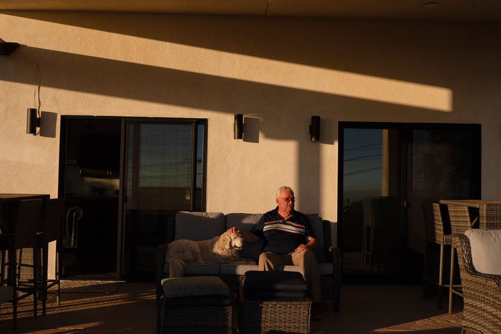 Ted Koerner, whose home was reduced to ash in the 2025 wildfires, sits on the porch of his newly rebuilt home, alongside his dog Daisy Mae, in Altadena, Calif., Dec. 11, 2025. (AP Photo/Jae C. Hong)