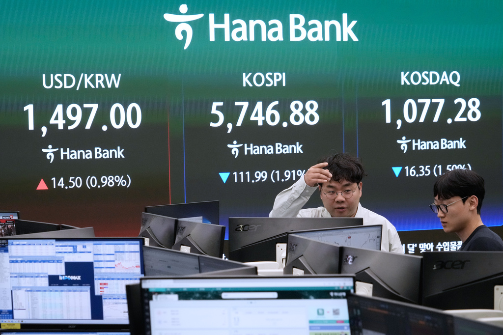 Currency traders work near a screen showing the Korea Composite Stock Price Index (KOSPI), top center, and the foreign exchange rate between U.S. dollar and South Korean won, top center left, at the foreign exchange dealing room of the Hana Bank headquarters in Seoul, South Korea, Monday, April 13, 2026. (AP Photo/Ahn Young-joon)