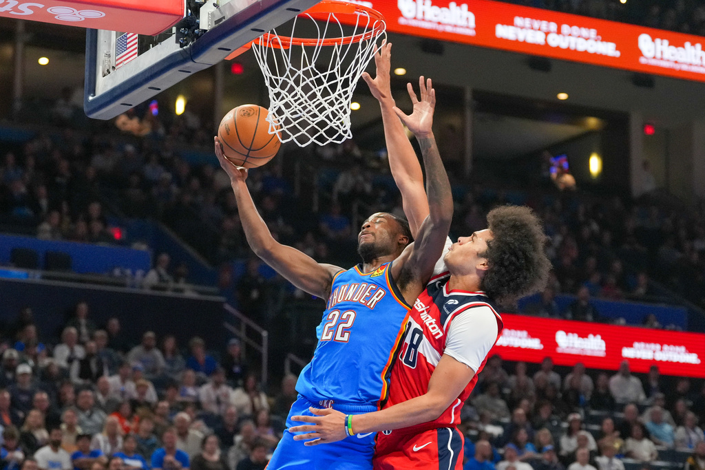 Oklahoma City Thunder guard Cason Wallace (22) shoots around Washington Wizards forward Kyshawn George, right, during the second half of an NBA basketball game, Thursday, Oct. 30, 2025, in Oklahoma City. (AP Photo/Kyle Phillips)