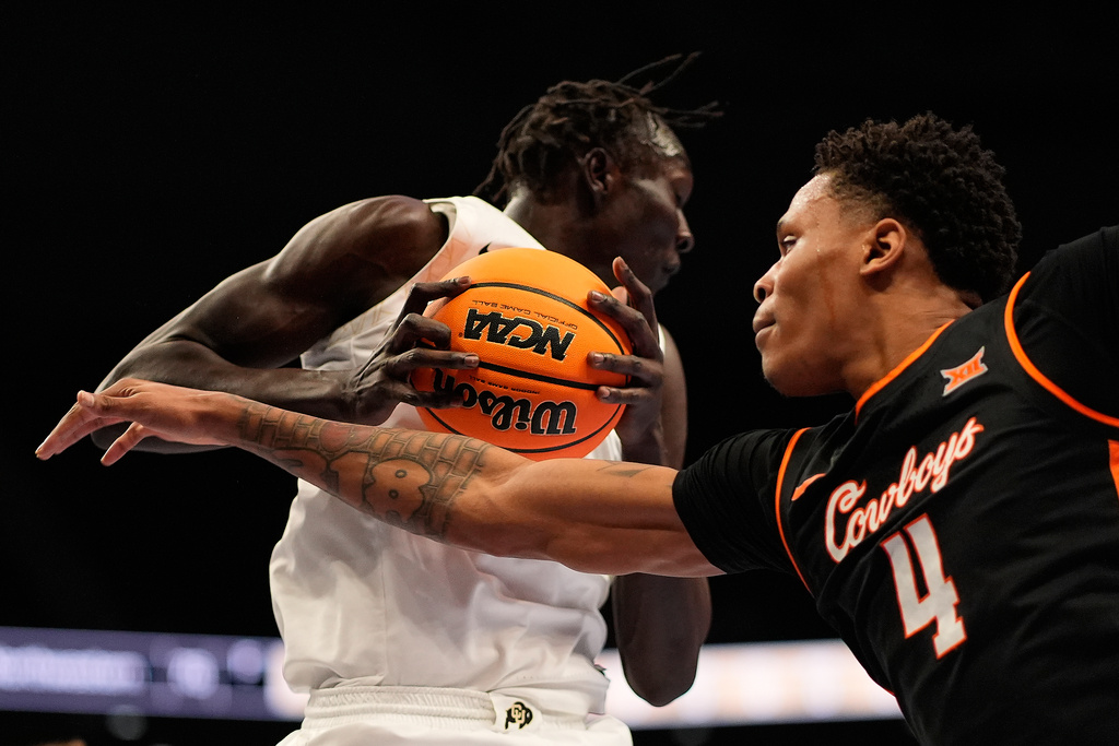 Oklahoma State forward Christian Coleman (4) tries to steal the ball from Colorado forward Bangot Dak (8) during the first half of an NCAA college basketball game at the Big 12 Conference tournament Tuesday, March 10, 2026, in Kansas City, Mo. (AP Photo/Charlie Riedel)