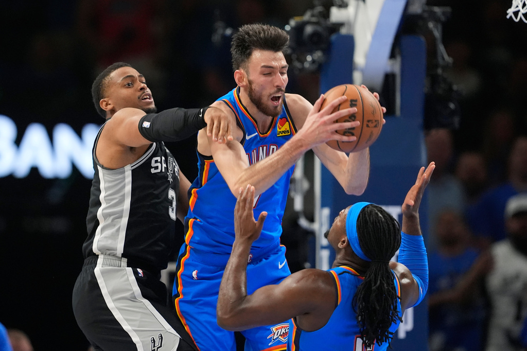 Oklahoma City Thunder center Chet Holmgren, center, grabs a rebound between San Antonio Spurs forward Keldon Johnson (3) and Thunder guard Luguentz Dort during the first half of Game 7 of the Western Conference finals of the NBA basketball playoffs series Saturday, May 30, 2026, in Oklahoma City. (AP Photo/Tony Gutierrez)