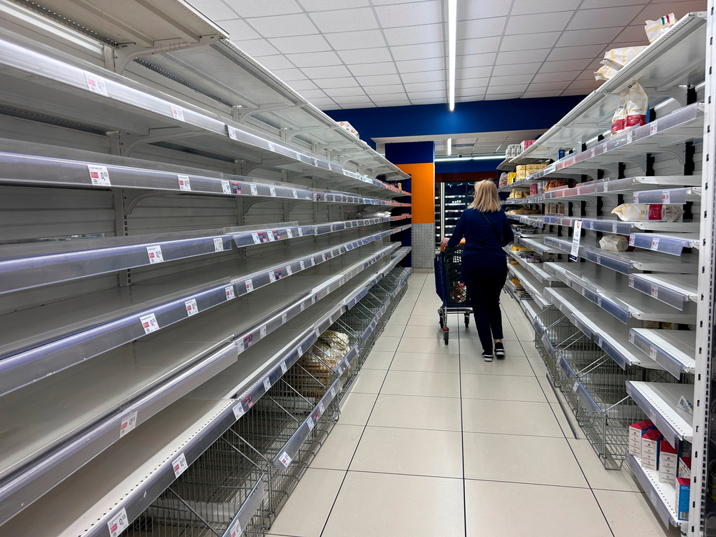 A woman walks past empty shelves at a supermarket in Naples, Italy, Tuesday, Oct. 20, 2026. (AP Photo/Alessandra Tarantino)
