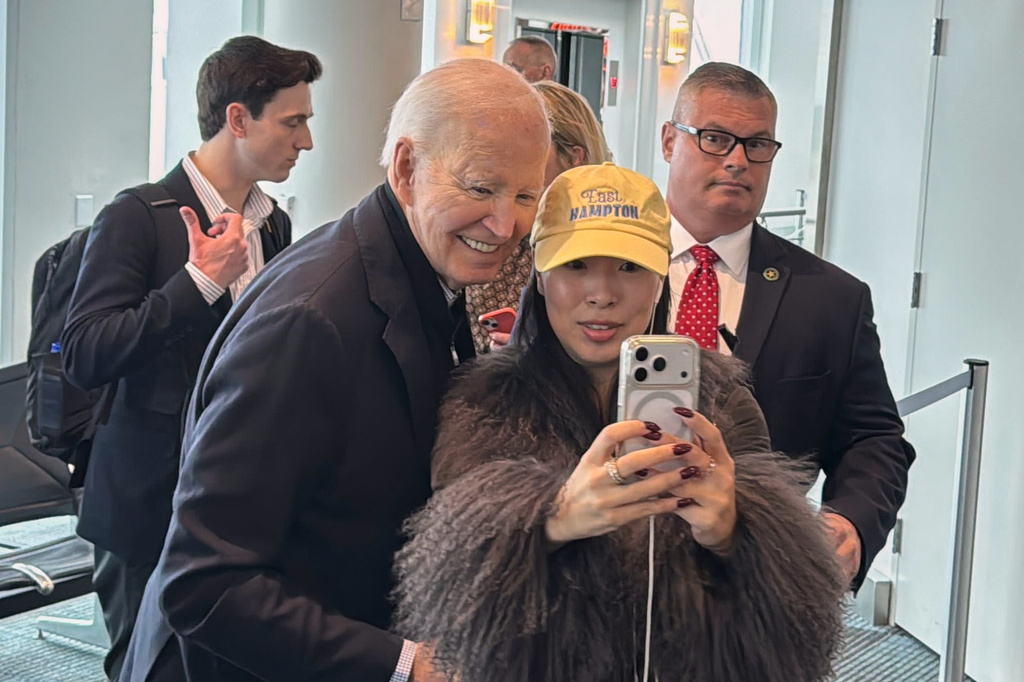 President Joe Biden is greeted by passengers awaiting an outgoing flight and poses for selfies, after his flight arrived, Friday, Feb. 27, 2026 in Columbia, S.C. (AP Photo/Meg Kinnard)