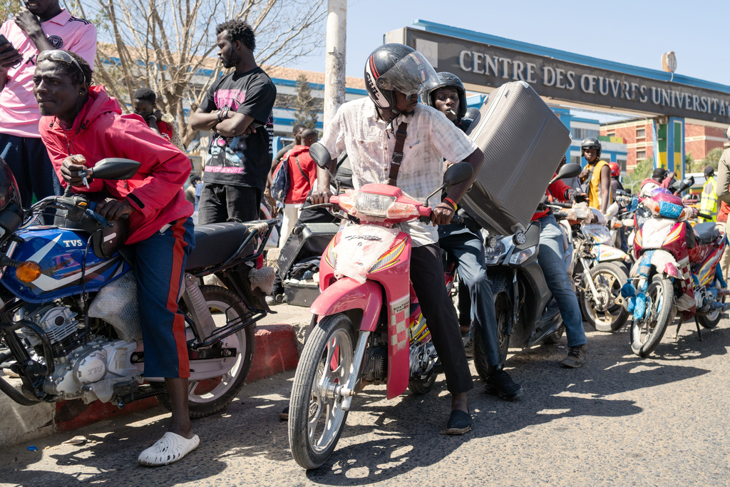 A student transports his belongings on a motorcycle taxi as he leaves the Cheikh Anta Diop University, which is being evacuated following the death of second year student Abdoulaye Ba, in Dakar Tuesday, Feb. 10, 2026. (AP Photo/Sylvain Cherkaoui)