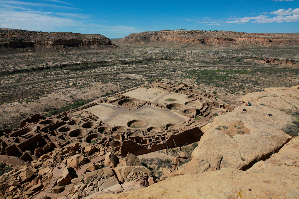 FILE - A hiker sits on a ledge above Pueblo Bonito, the largest archeological site at the Chaco Culture National Historical Park, in northwestern New Mexico, Aug. 28, 2021. (AP Photo/Cedar Attanasio, File)