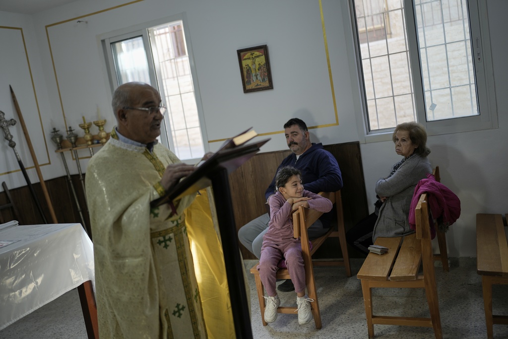 Priest Maurice El Khoury, left, leads Sunday Mass inside a room usually used as a residence for visiting bishops next to St. George Melkite Catholic Church, which was destroyed in an Israeli airstrike, in the town of Dardghaya, southern Lebanon, Sunday, Nov. 16, 2025. (AP Photo/Hassan Ammar)