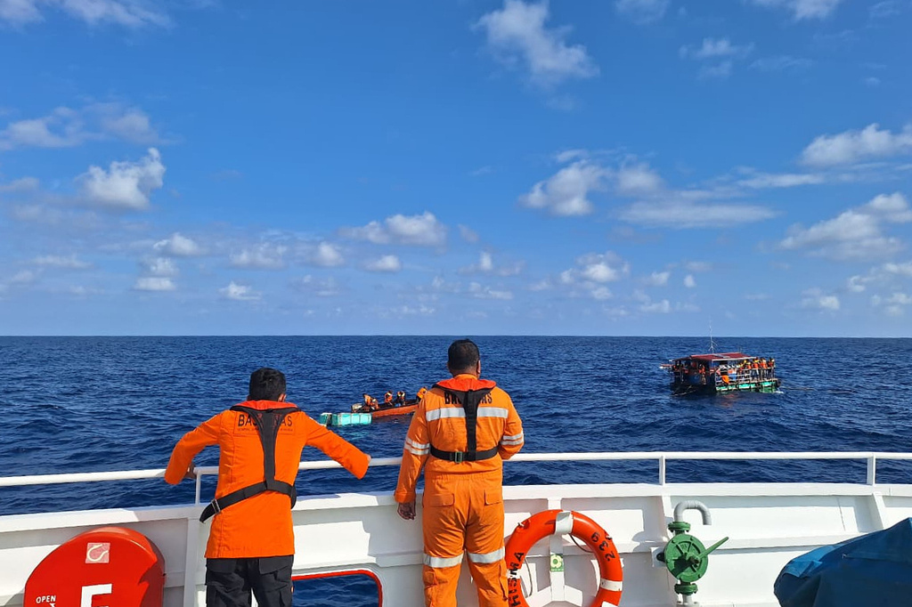 In this photo released by the Indonesian National Search and Rescue Agency (BASARNAS), crew look on as a rescue ship approaches a raft to evacuate the survivors boat that sank on Monday, in the waters off Taliabu Island, Indonesia, Tuesday, March 31, 2026. (BASARNAS via AP)