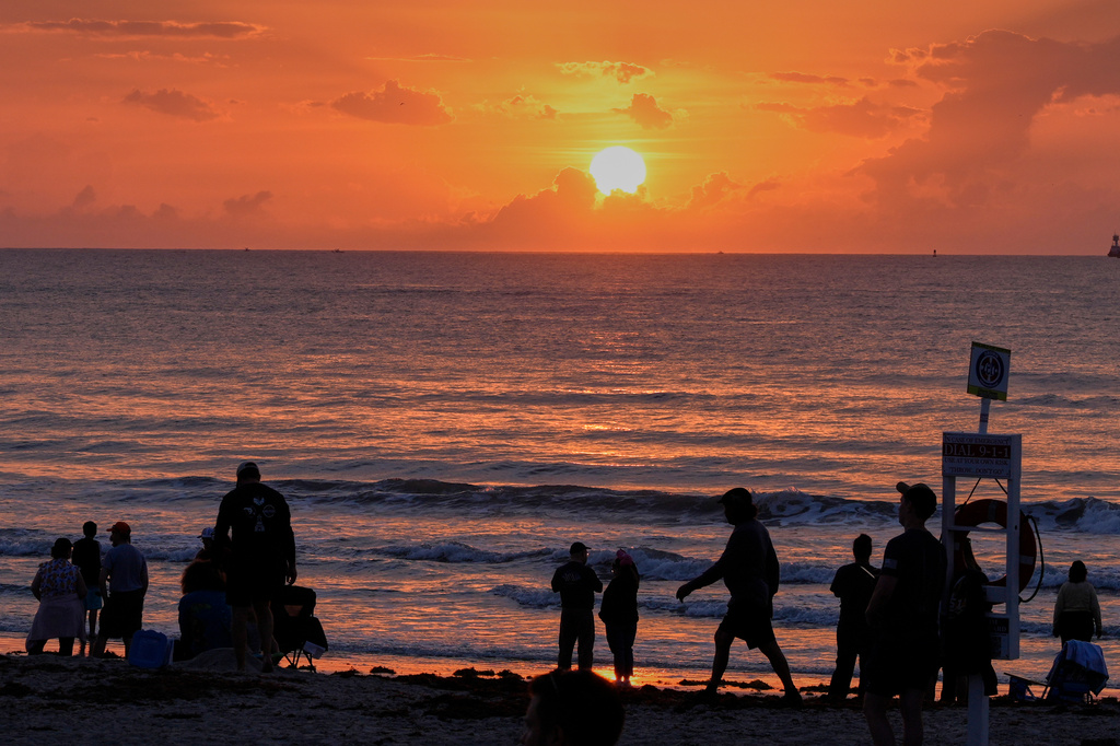 Spectators watch the sunrise from the beach at Cherie Down Park in Cape Canaveral, Fla., as they wait to watch the launch of the Blue Origin New Glenn rocket from the Cape Canaveral Space Force station, Sunday, April 19, 2026, in Cape Canaveral, Fla. (AP Photo/John Raoux)
