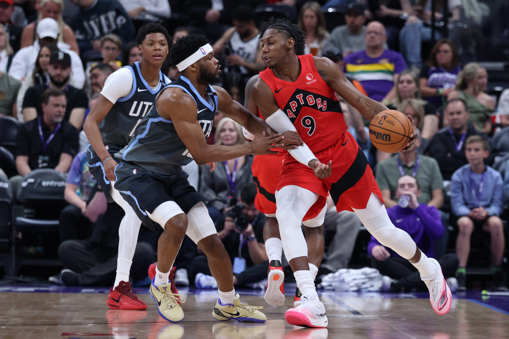 Toronto Raptors forward RJ Barrett (9) moves the ball as Utah Jazz guard Elijah Harkless, left, defends during the first half of an NBA basketball game, Monday, March 23, 2026, in Salt Lake City. (AP Photo/Rob Gray)