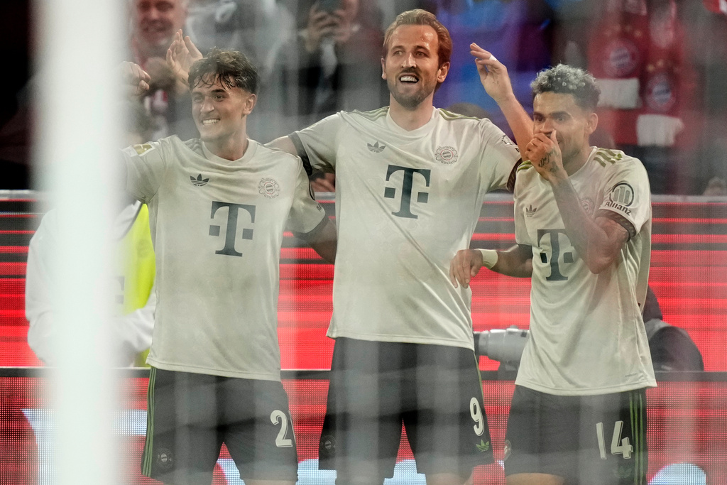 Bayern's Harry Kane, centre, seen through the net, celebrates after scoring his side's third goal during the Bundesliga soccer match between Bayern Munich and Werder Bremen at the Allianz Arena in Munich, Germany, Friday, Sept. 26, 2025. (AP Photo/Matthias Schrader)