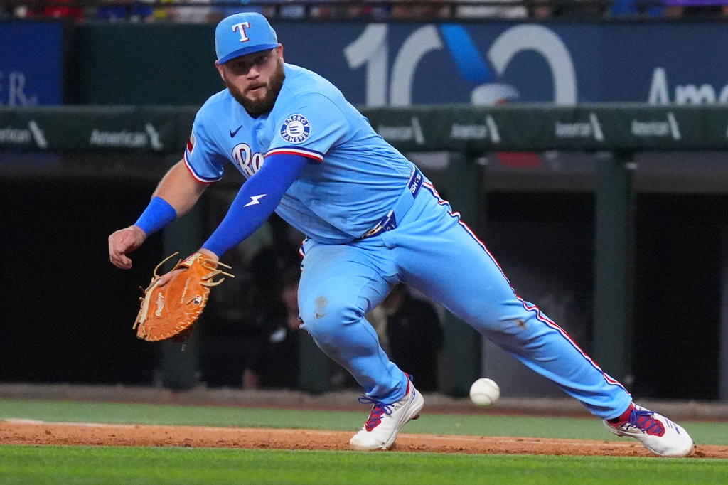 Texas Rangers first baseman Jake Burger tries to reach a single hit by Detroit Tigers' Kevin McGonigle during the fifth inning of a baseball game, Sunday, July 5, 2026, in Arlington, Texas. (AP Photo/LM Otero)