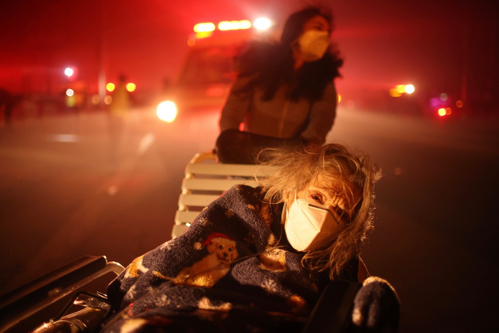 A resident of a senior center is rushed into a vehicle while evacuating as the Eaton Fire approaches, Jan. 7, 2025, in Altadena, Calif. (AP Photo/Ethan Swope, File)