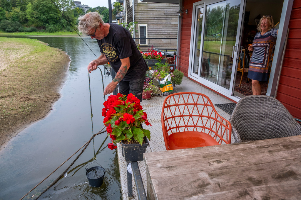 Houseboat owners pull up water for plants from the Waal river in Nijmegen, Netherlands, Thursday, July 30, 2026, during drought conditions. (AP Photo/Patrick Post)
