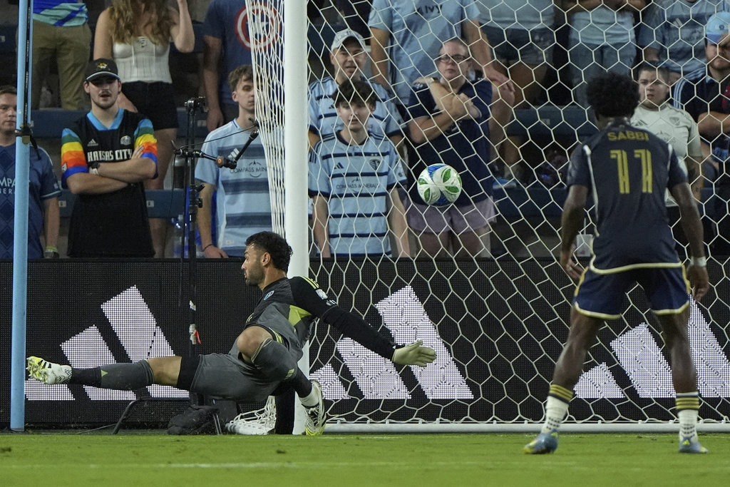 A ball kicked by Vancouver Whitecaps midfielder Kenji Cabrera gets past Sporting Kansas City goalkeeper John Pulskamp, left, to score a goal during the first half of an MLS soccer match Saturday, Sept. 20, 2025, in Kansas City, Kan. (AP Photo/Charlie Riedel)