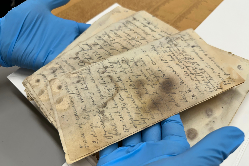 State Historical Society of North Dakota Deputy State Archivist Lindsay Meidinger holds pages of the diary of Mark Kellogg, a reporter killed during the Battle of the Little Bighorn in 1876, at the North Dakota Heritage Center and State Museum in Bismarck, N.D., Wednesday, June 24, 2026. (AP Photo/Jack Dura
