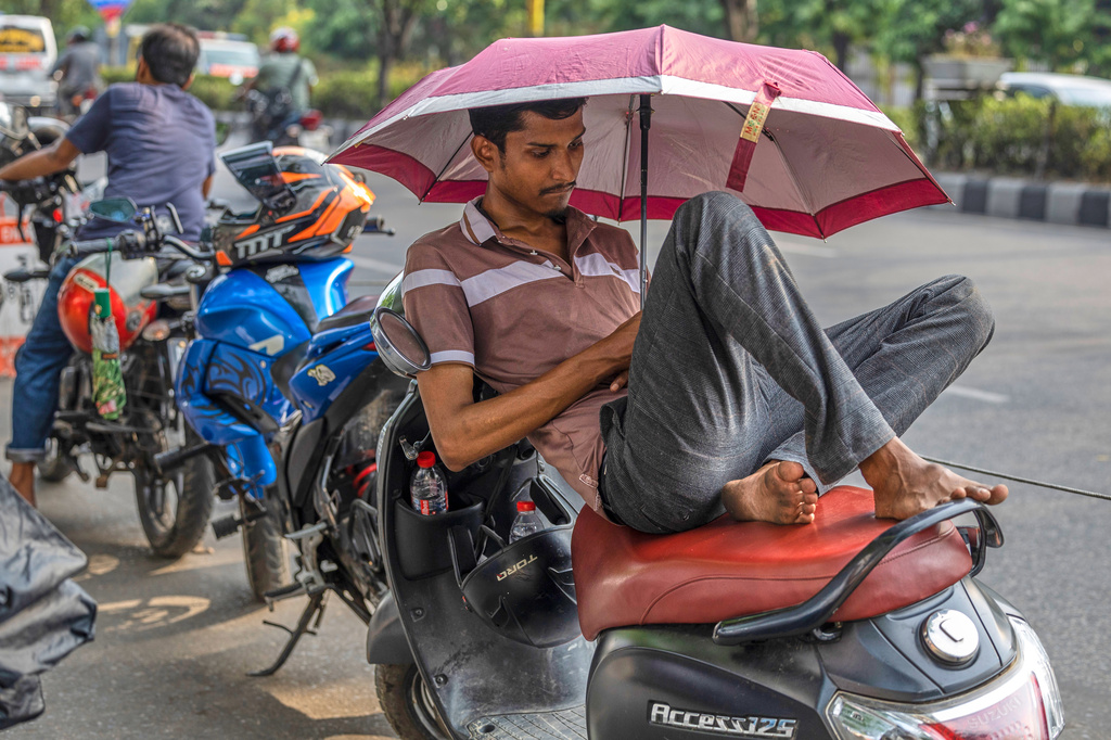 A motorcyclist rests under an umbrella while waiting in line for fuel at a petrol station in Dhaka, Bangladesh, Thursday, April 23, 2026. (AP Photo/Abdul Goni)