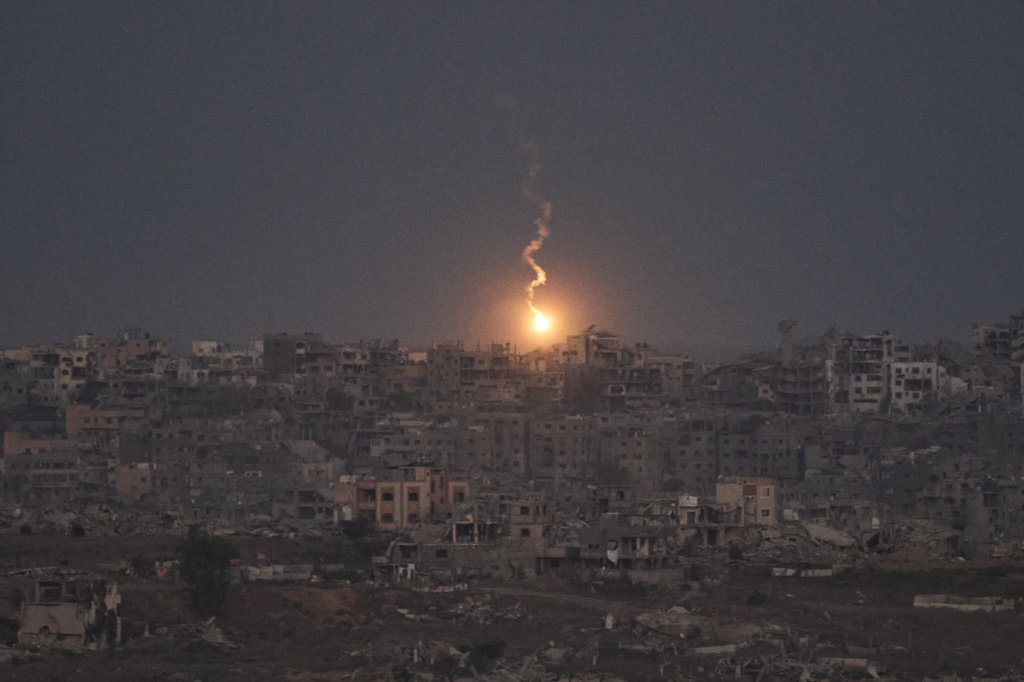 An Israeli army flare drifts over buildings destroyed during Israeli ground and air operations in the northern Gaza Strip, as seen from southern Israel, Monday, Oct. 6, 2025. (AP Photo/Leo Correa)