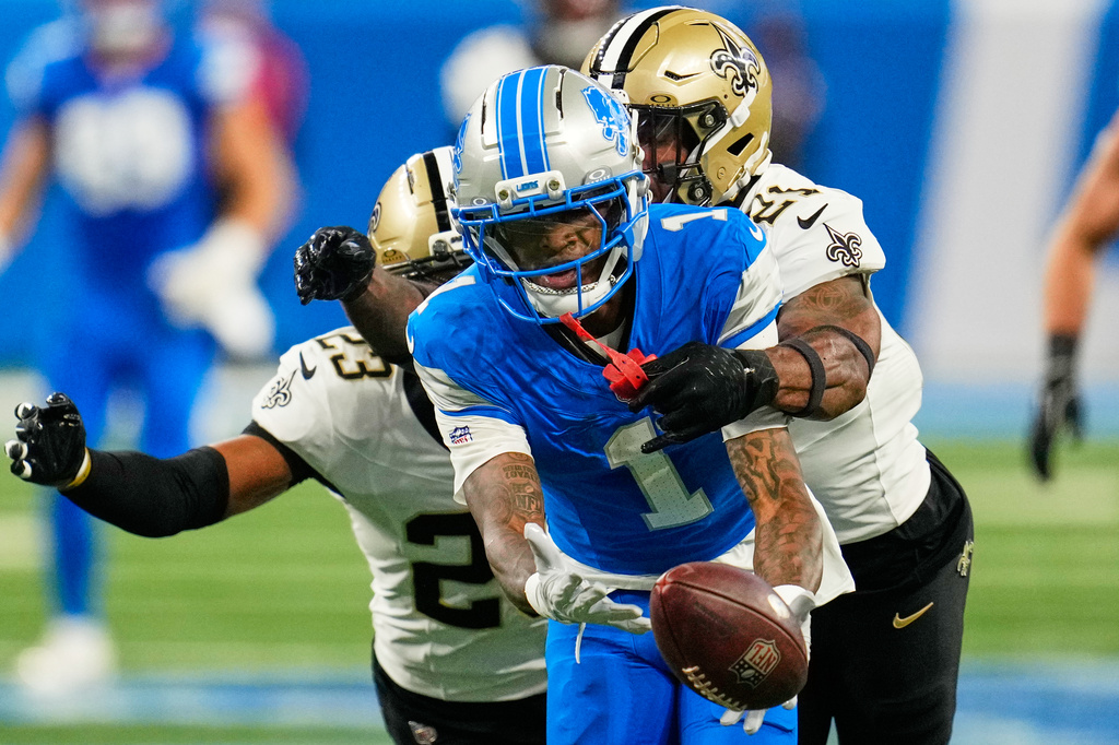 Detroit Lions wide receiver Jameson Williams (1) can't hold into a pass as he is defended by New Orleans Saints safety Justin Reid (21) and safety Julian Blackmon (23) in the first half of an NFL football game, Sunday, Sept. 13, 2026, in Detroit. (AP Photo/Paul Sancya)