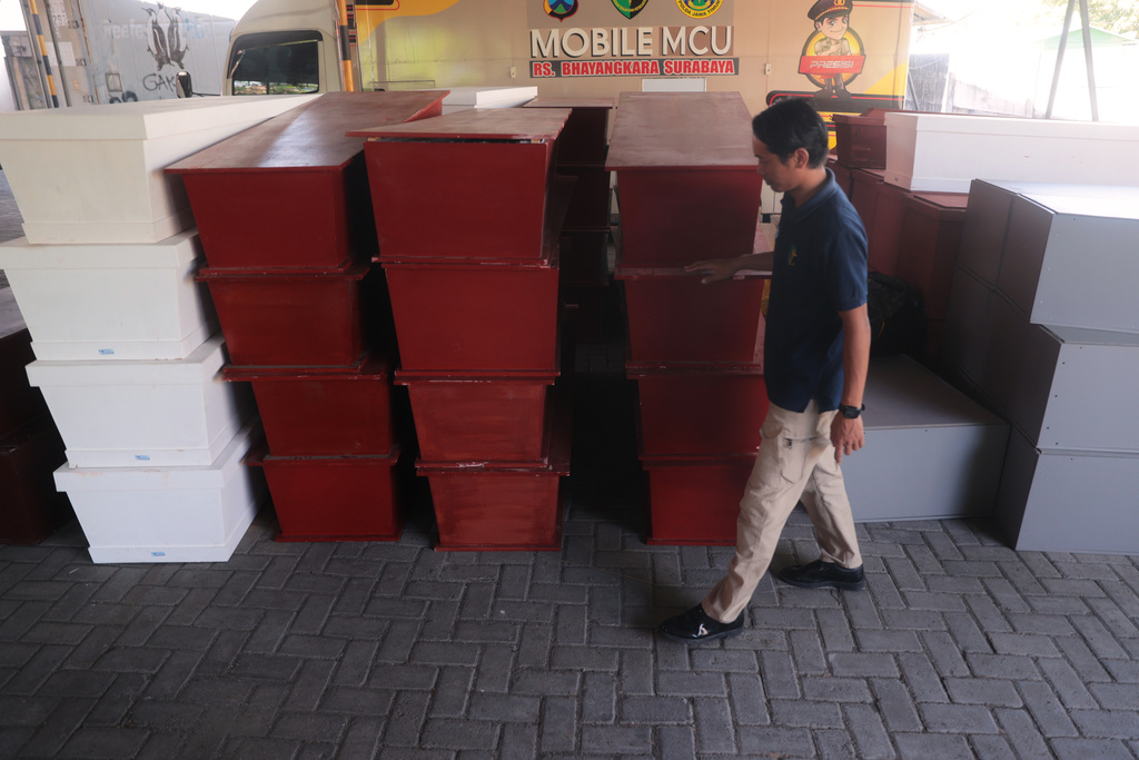 A staff inspects coffins prepared for the victims of a building that collapsed at an Islamic boarding school, at the police hospital in Surabaya, East Java, Indonesia, Sunday, Oct. 5, 2025. (AP Photo/Trisnadi)