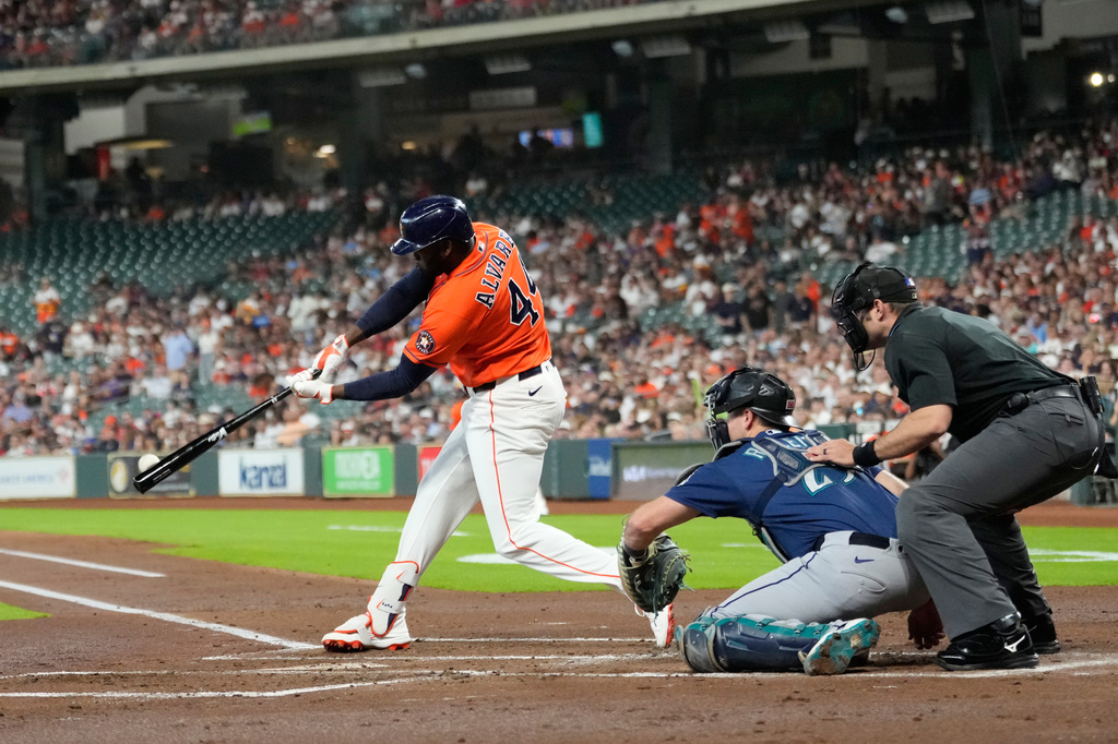 Houston Astros' Yordan Alvarez (44) hits a home run as Seattle Mariners catcher Cal Raleigh reaches for the pitch during the first inning of a baseball game Friday, Aug. 14, 2026, in Houston. (AP Photo/David J. Phillip)