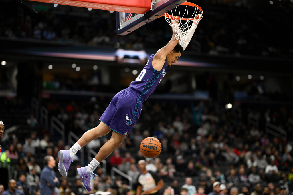 Charlotte Hornets guard Josh Green (10) swings from the rim after dunking during the first half of an NBA basketball game against the Washington Wizards, Sunday, Feb. 22, 2026, in Washington. (AP Photo/Nick Wass)